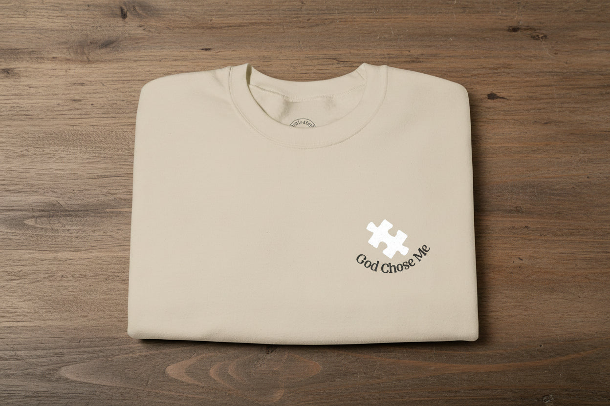 "God chose me" autism puzzle piece faith-based embroidery sweatshirt gildan 18000 sweatshirt sand white puzzle piece. folded on table